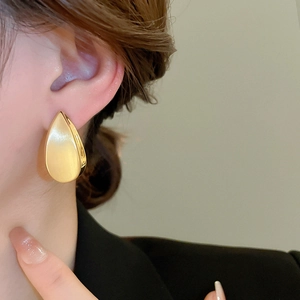Dettaglio di grandi orecchini a goccia placcati oro 18k con finitura in metallo spazzolato
