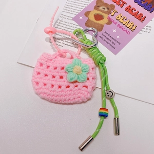 Détail d'un mini porte-clés sac en tricot rose avec motifs floraux et dragonne tressée