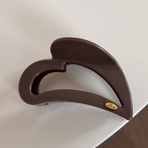 Macro view of dark brown heart hair claw clip with golden Love engraving on metal plaque