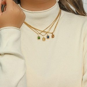 Detail of layered gold necklaces with colorful rectangular zircon pendants on a model