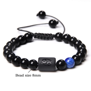 Cancer zodiac braided bracelet with 8mm black beads and blue gemstone on white background