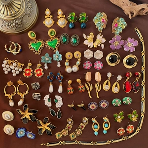Collection of vintage gold earrings and a bracelet with pearls and gemstones on brown fabric