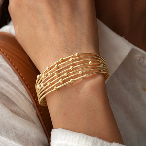 Detail shot of multi-layer golden beaded bracelet styled with bohemian chic aesthetic