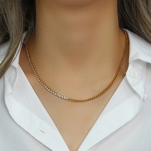 Detail of gold Cuban link chain with rhinestone inlay worn by a model on a white shirt