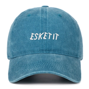 Detail of white ESKETIT letter embroidery on navy blue washed denim baseball cap