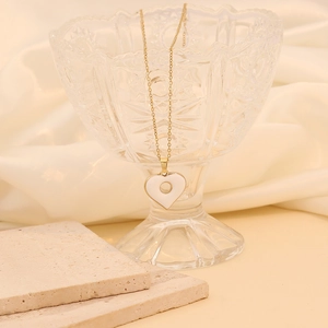 Détail du pendentif cœur doré avec émail blanc sur un verre décoratif élégant