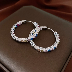 Close-up of circular hoop earrings with multi-colored cubic zirconia on dark satin