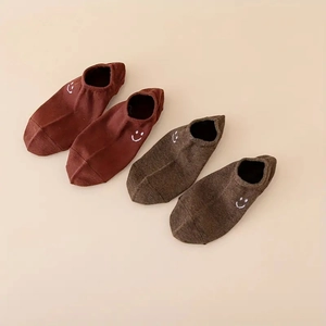 Detail of knit cotton ankle socks in dark coffee and light brown with smiley embroidery