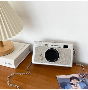 Creative silver camera crossbody bag with rhinestones and chain strap on desk