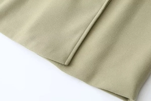 Detail view of olive green wool coat showing precision stitching and thick fabric texture
