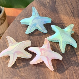 Detail of four colorful laser starfish hair claws in blue, green, pink and cream