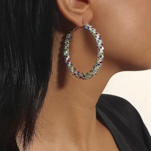 Close-up of a large round earring with colorful rhinestones on a female model
