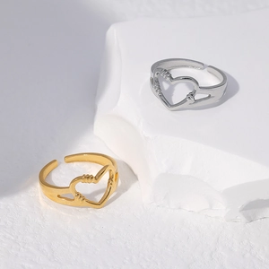 Detailed macro view of gold and silver heart cutout adjustable rings on a stone surface