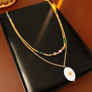 Detail of vintage sunburst pendant necklace with multi-colored beads on black display
