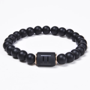 Detailed macro of black onyx beaded bracelet with Gemini symbol and rose gold spacers
