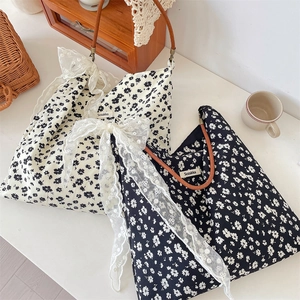 Détail de sacs fourre-tout à fleurs avec grands nœuds en dentelle et anses en cuir marron