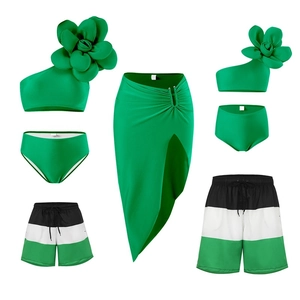 Detailed flat lay of family matching swimsuits with green floral and striped design