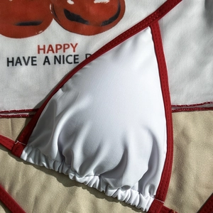 Detail of white bikini top with red trim and printed mesh fabric featuring Happy text