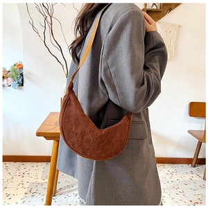 Brown corduroy dumpling bag with adjustable strap worn as a stylish crossbody bag