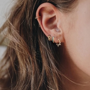 Close-up of woman wearing a gold chain ear cuff set with turquoise and crystal accents
