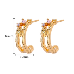 Close-up of golden floral C-shape earrings with colorful gems and size markings