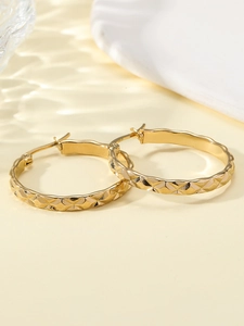 Detailed macro view of gold-plated stainless steel hoop earrings with rhombus pattern texture