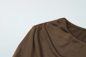 Detailaufnahme des braunen Kleides mit eleganten Schulterfalten und glattem Halsausschnitt
