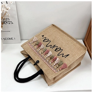 Detail of jute tote bag featuring Mamma print and colorful tassel decoration