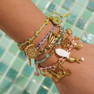 Close-up of ocean-themed braided bracelets with golden nautical charms and sea life details