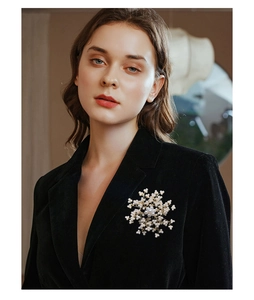 Detailed view of elegant snowflake brooch with pearls pinned on a black suit jacket