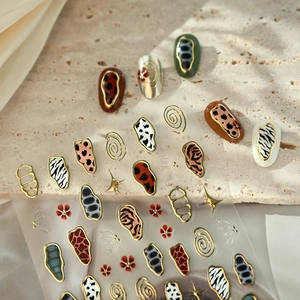 French animal print nail stickers with gold leopard and zebra patterns on a stone slab