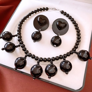 Detail view of black acrylic heart and circle jewelry set in a white gift box