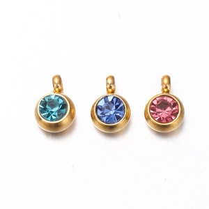 Detailed view of three gold pendants set with teal, blue, and pink faceted gemstones