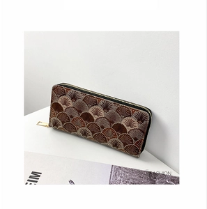 Detail of a brown woven wallet with shell patterns and a sturdy gold zipper closure