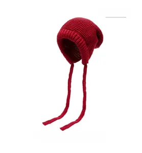 Detail of claret knit winter hat with earflaps and long ties in soft chunky texture