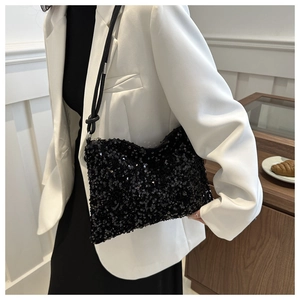 Détail d'un sac à paillettes noires scintillantes avec fine bandoulière en cuir noir