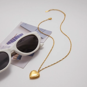 Detail of an openable heart-shaped pendant with vintage texture on a gold water wave chain