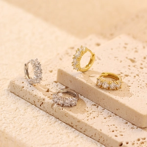 Close-up of gold and silver S925 sterling silver huggie earrings with cubic zirconia stones