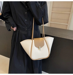 Dettaglio della borsa tote bicolore con corpo crema, patta marrone e fibbia in metallo oro