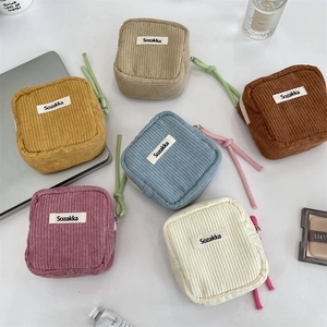 Detailed flat lay of corduroy cosmetic bags in various colors on a white desk setup