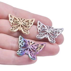 Three colorful stainless steel hollow butterfly pendants held in hand for size context