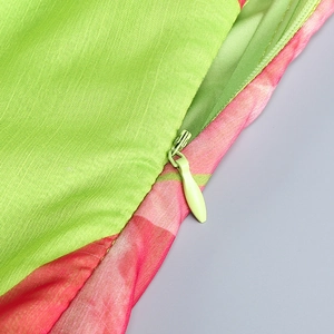 Détail de la fermeture éclair invisible sur le tissu sergé vert et rose de la robe