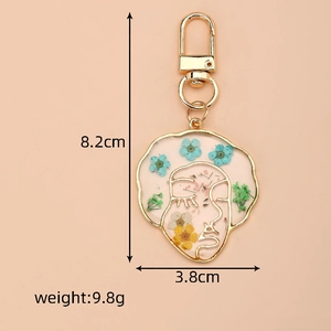 Detail showing dimensions of abstract face resin keychain with colorful dried flowers
