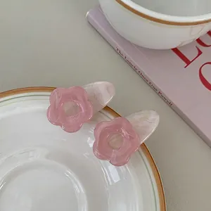 Close-up of two pink flower hair clips with marble texture on a ceramic plate