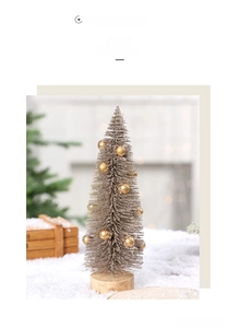 Detailed view of champagne gold mini Christmas tree with glitter and wooden base on snow