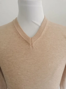 Detail des V-Ausschnitts und der feinen Strickstruktur eines beigen Herrenpullovers
