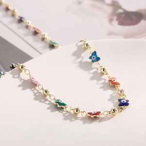 Detail of gold chain necklace with colorful enamel butterfly and evil eye charms