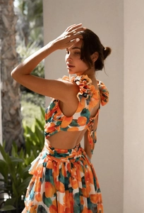 Detail of floral backless dress with layered ruffles and orange fruit print design