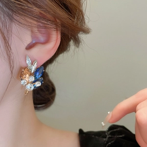 Detail of luxury teardrop stud earrings with blue and champagne crystals on model