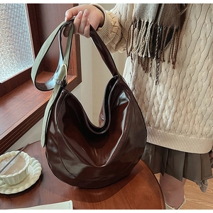 Detail of a large brown glossy PU leather Hobo bag with olive green wide shoulder strap